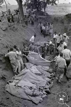 Bodies of bombing victims being moved into a mass grave after the Freedom Camp massacre